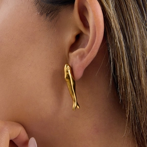 Detailed view of 18k gold plated stainless steel fish earrings worn by a model