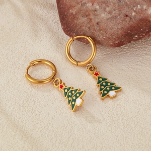 Macro view of gold Christmas tree earrings with colorful enamel on a textured background