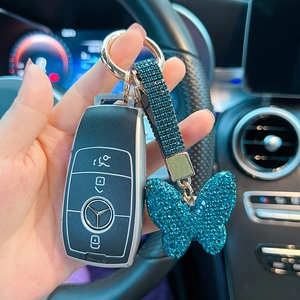 Detail of dark blue rhinestone butterfly keychain on car key inside a vehicle