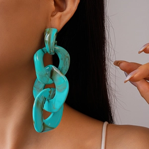 Close-up of oversized turquoise acrylic chain earrings with brown marble texture
