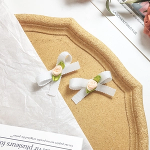 Vue détaillée de nœuds en ruban blanc faits main avec roses en tissu et feuilles vertes