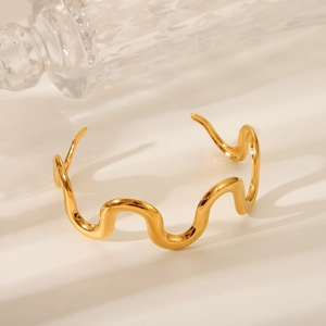18K gold plated stainless steel wave bangle with a geometric open design on a white surface