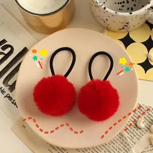Detail of red faux fur pom-pom hair ties with elastic bands in a cozy festive setting