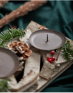 Close-up of birch wood candle holder with pine cones, berries, and metal tray detail
