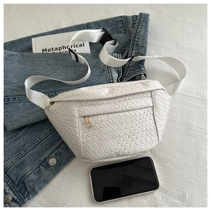 White woven fanny pack with gold zipper shown on denim jacket next to a smartphone