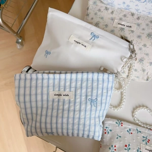 Detail of blue and white floral fabric pouches with zipper and pearl chain accessory