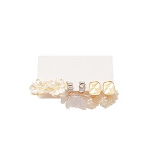 Set di tre paia di orecchini con fiori, perle e zirconi su sfondo bianco