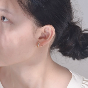 Macro side view of a gold-plated seahorse stud earring with micro-inlaid zircons on a model
