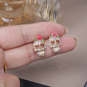 Punk gothic skull earrings with pink roses and colorful crystals held in hand