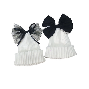 White ribbed knit beanie hats featuring lace bows and elegant pearl embellishments