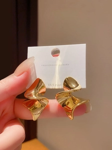 Détail de boucles d'oreilles dorées géométriques torsadées avec tiges en argent S925