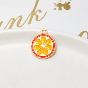 Detail of orange slice alloy pendant with gold plating on a white ceramic tray