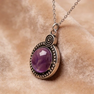 Détail d'un pendentif vintage en résine violette avec spirale argentée et chaîne