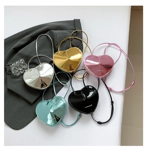 Flachbild von fünf herzförmigen Umhängetaschen in Silber, Gold, Rosa, Blaugrün und Schwarz