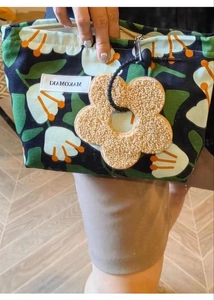 Detail of tropical print canvas makeup bag with soft plush flower charm and sturdy zipper