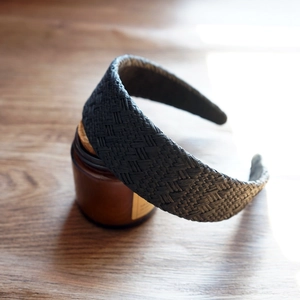 Close-up of black raffia headband with woven texture on a natural wooden table