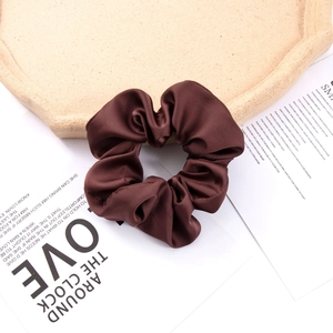Close-up of brown satin silk oversized scrunchie with elegant folds and texture