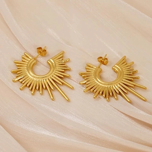 Modern gold sunburst stud earrings with irregular geometric rays on champagne silk fabric