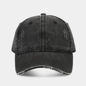 Detail showing the distressed edges and worn-out holes on a washed black baseball cap
