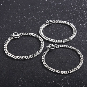 Trois bracelets gourmettes en acier titane argenté avec fermoir OT sur fond noir