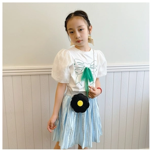 Detail of child wearing a black flower-shaped shoulder bag with metallic pleated skirt