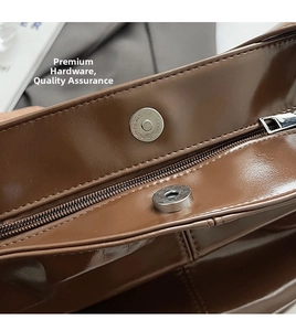 Dettaglio della borsa in pelle marrone lucida con chiusura magnetica argento e zip in metallo