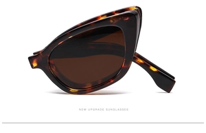 Detail view of foldable cat-eye sunglasses with thick tortoiseshell frame and brown lenses