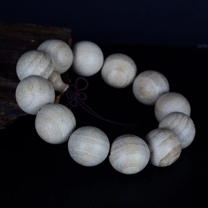 Polished natural camphor wood prayer beads with traditional knot on dark background