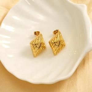 Elegant gold rhombus stud earrings with textured finish on a white shell tray