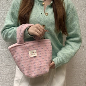 Pink plush tote bag with embroidered brand label held by a model for a lifestyle view
