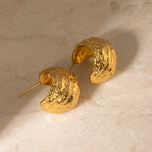 Detail of 18k gold plated stainless steel C-shaped earrings with hammered texture finish