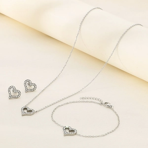 Macro view of silver heart jewelry set featuring sparkling pavé crystals on a soft beige base