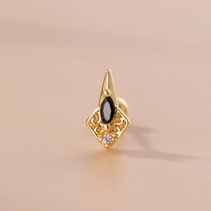 Detail of vintage gold cartilage stud with black oval gemstone and filigree metal work