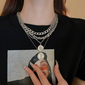 Detail of multi-layer silver coin necklace featuring Elizabeth II pendant on chunky chains