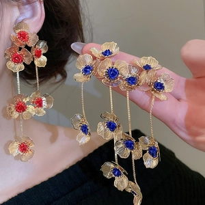 Detail of red and blue hollow floral tassel earrings with golden petals and long chains