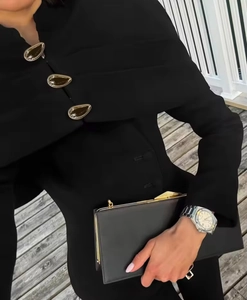 Close-up of black slim-fit jacket featuring three elegant gold water-drop metal buckles