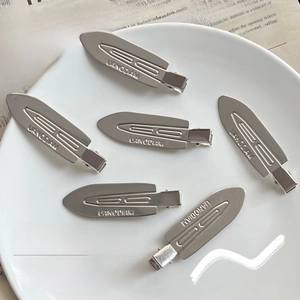 Set of 6 minimalist silver metal hair clips with embossed lettering in a ceramic bowl