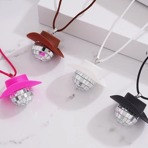 Sparkly disco ball cowboy hat necklaces in pink, white, brown and black on marble surface