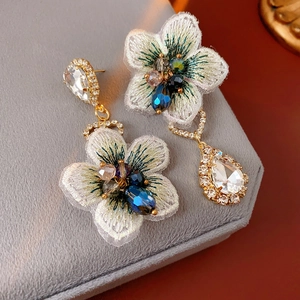 Détail de boucles d'oreilles fleurs en tissu vintage avec perles et cristal goutte
