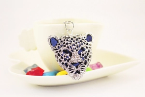 Detailed view of blue leopard head keychain with silver rhinestones on white ceramic