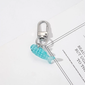 Close-up of a blue translucent resin fish keychain with white dots and silver clasp
