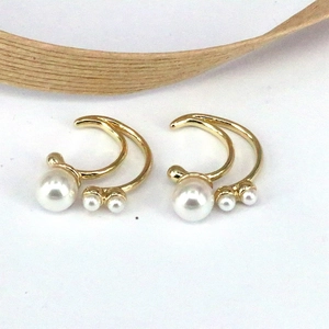 Detailed shot of gold-plated double-curved ear clips with three white pearls on each