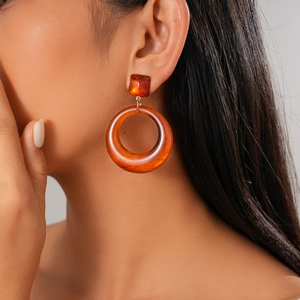 Gros plan de boucles d'oreilles créoles géométriques en résine écaille sur un modèle