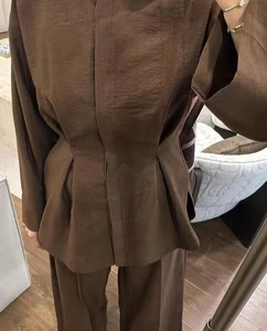 Detail of brown pleated suit set showing the unique vertical texture fabric and fit