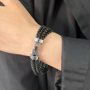 Close-up of multi-layer black beaded bracelet with silver metal buckle on wrist
