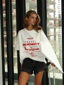 T-shirt bianca oversize con grafica vintage wanderlust e stampa di aereo rosso