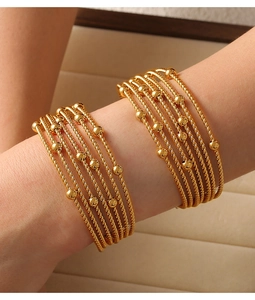 Detail of gold-layered titanium steel bracelets featuring twist texture and round beads