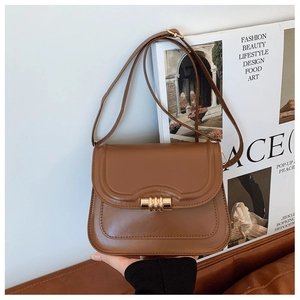 Gros plan d'un sac besace en cuir marron caramel avec une boucle dorée élégante en métal