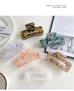 Detailed flat lay of six large square acrylic hair claw clips in various floral patterns