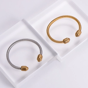 Detailed view of two twisted cable stainless steel bangles in silver and gold finishes